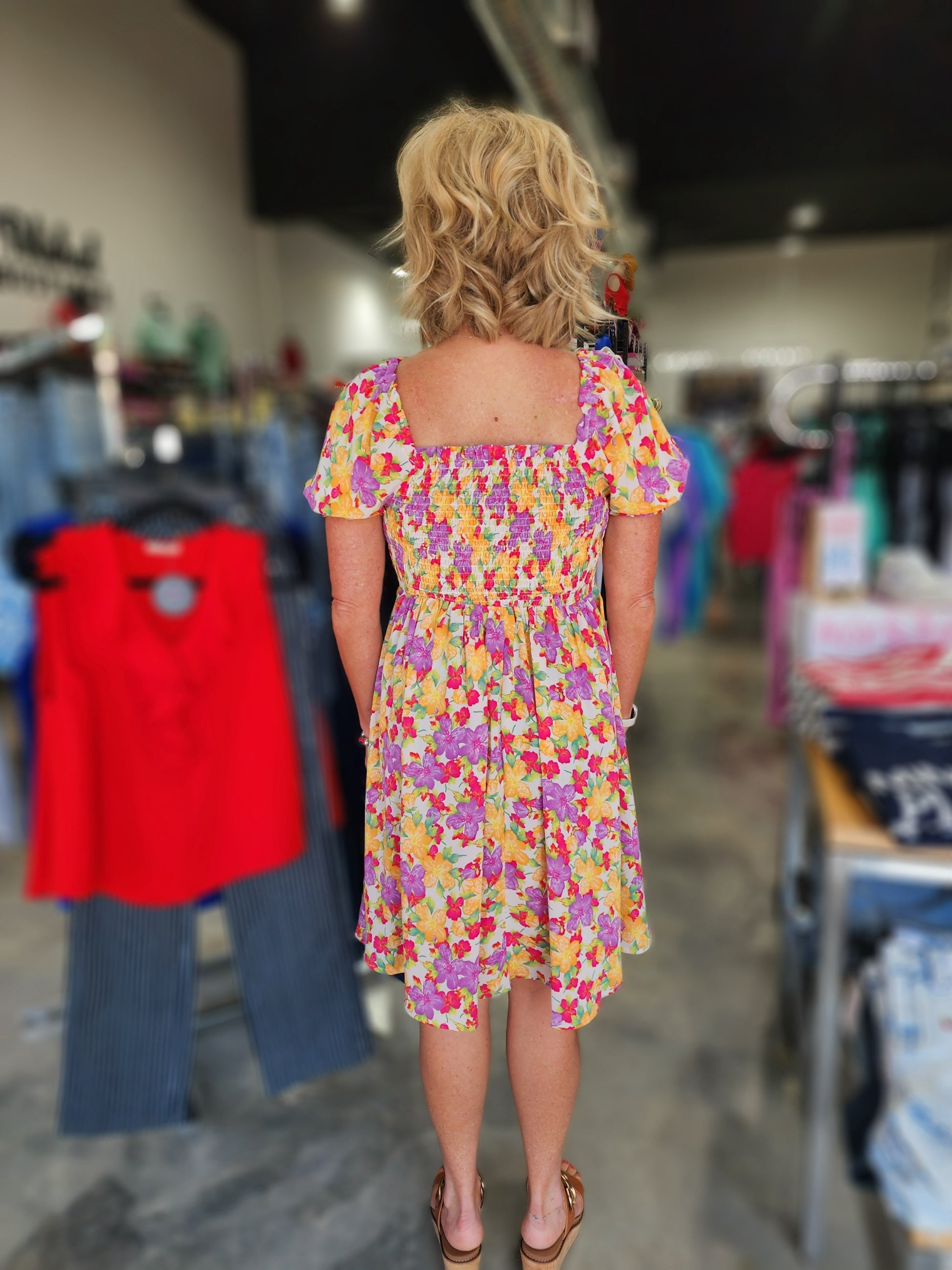 Woman wearing a colorful floral dress in a store setting